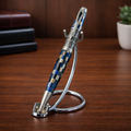 Luxury blue and gold striped pen with ornate detailing on a silver stand, office desk background