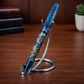 Blue and gold marbled fountain pen on chrome stand, wooden desk background.