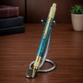 Luxury teal and gold ballpoint pen on metal stand, wooden desk background, elegant office decor