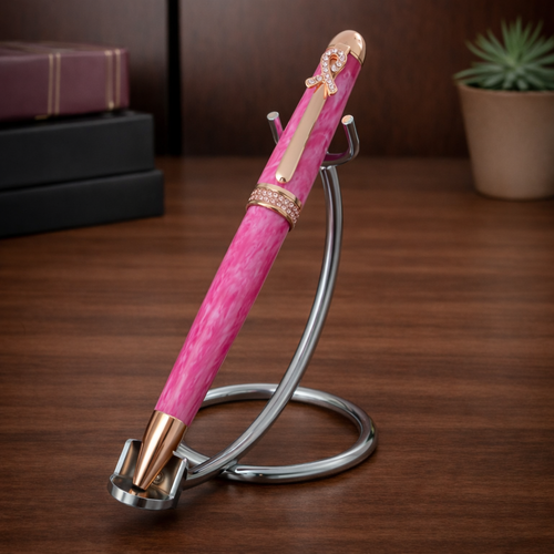 Elegant pink marbled pen with gold accents on a metal stand, on a wooden desk